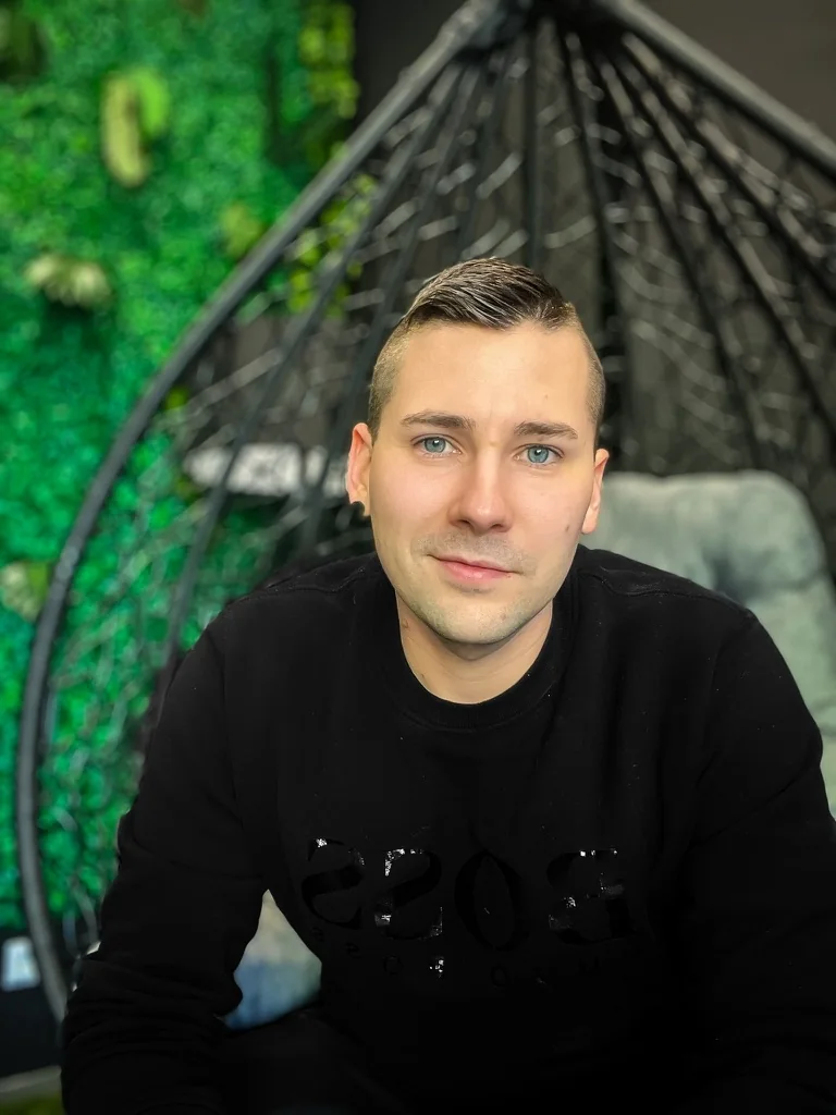 Chris Fuhrmann im Hängesessel vor einer grünen Pflanzenwand